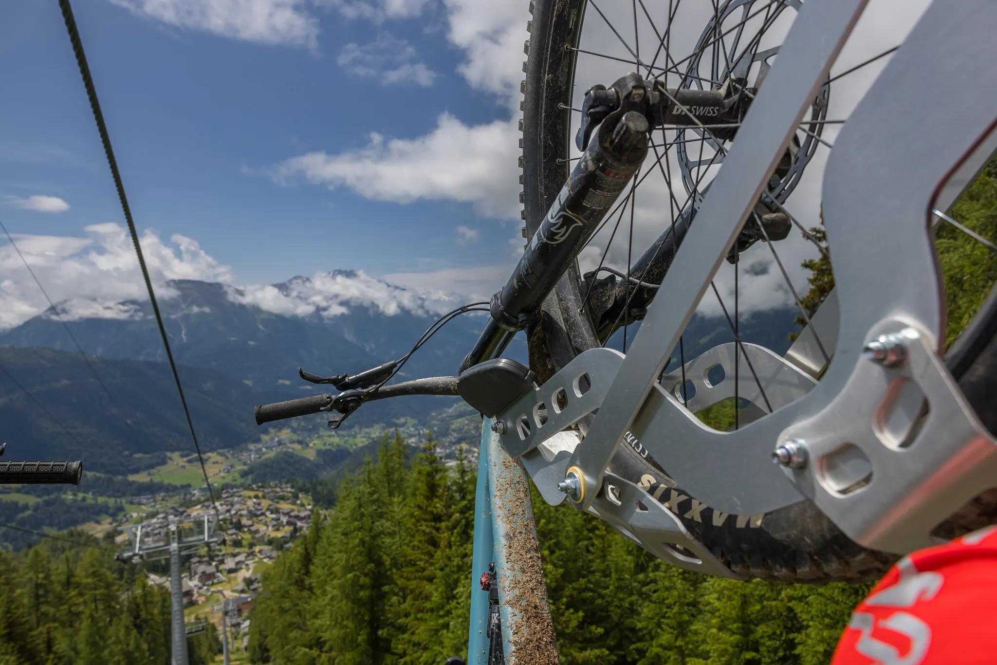 Sessellift mit montierten Bike Cips und eingehängten Mountainbikes fährt in Richtung Bergstation. Blick vom Sessellift an der Befestigung vorbei Richtung Tal. 