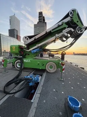 Das Bild zeigt eine Energiekette auf einer großen Trommel. Am linken Bildrand ist das Heck eines Containerschiffes zu erkennen. Die e-kette auf Trommel  dient der mobilen Landstromversorgung. Das System heußt e-chain REEL.