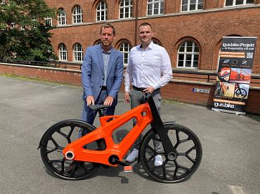 Der Kieler Oberbürgermeister Dr. Ulf Kämpfer und Alexander Welcker von igus  mit einem Kunststoffrad