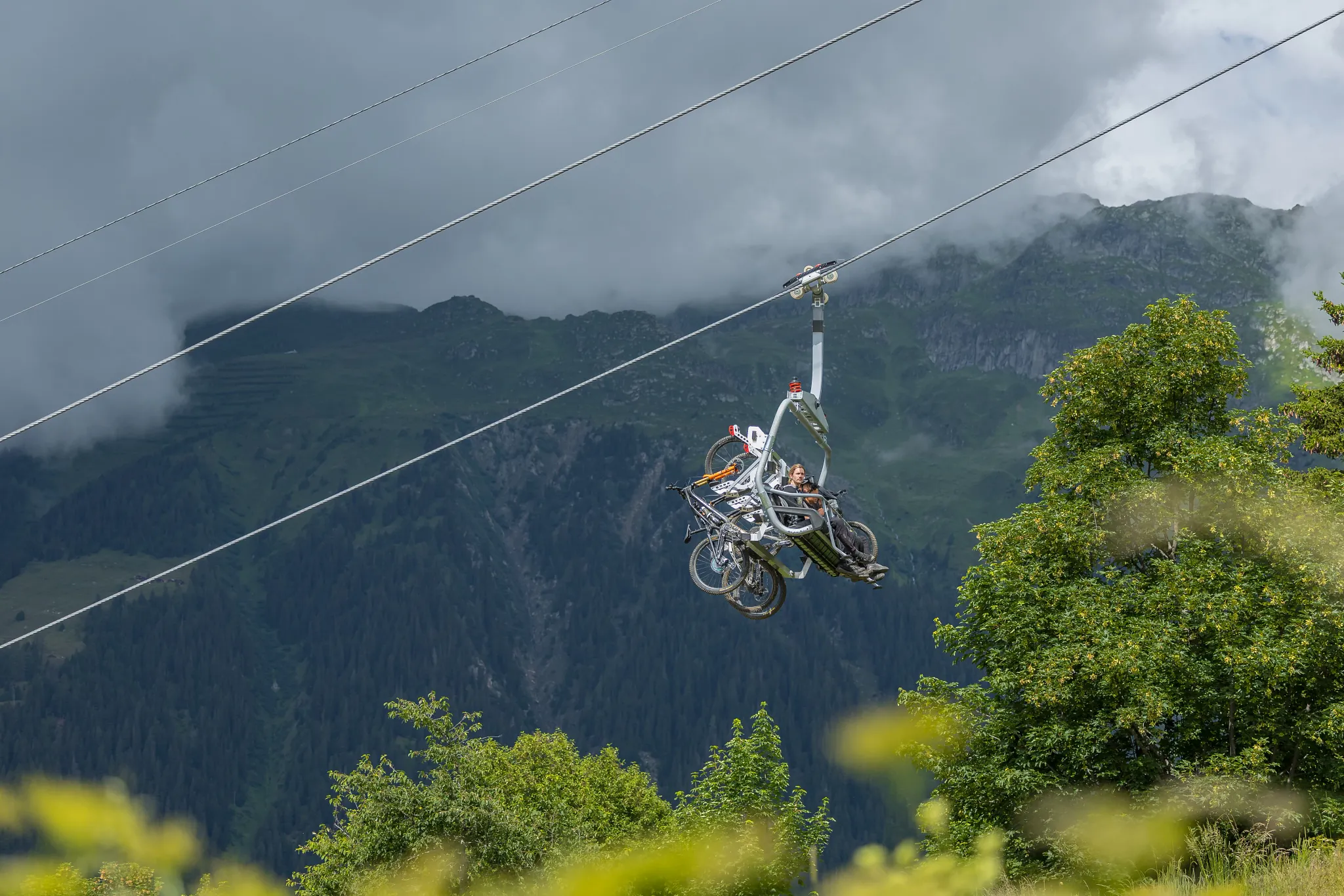Sessellift mit montierten Bike Clips und eingehängten Mountainbikes fährt in Richtung Bergstation.