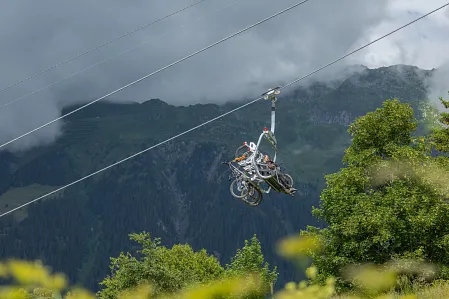 A chair lift fitted with bike clips that securely hold mountain bikes heads up to the summit station.