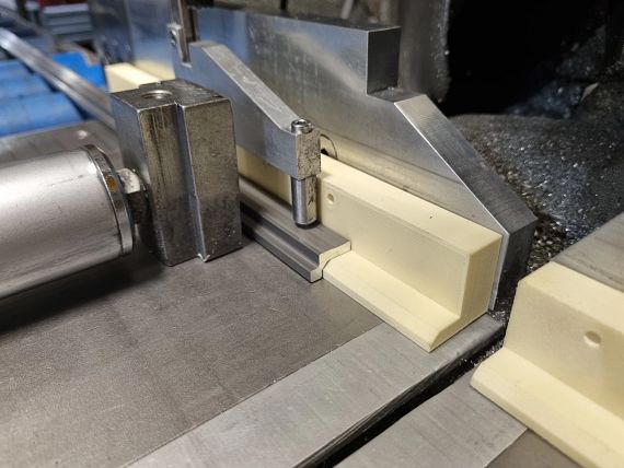 Un dispositivo fabricado con iglidur I190 en impresión 3D para que los rieles descansen en ángulo recto sobre la superficie de trabajo de la sierra de perfil.
