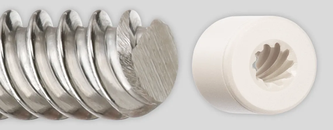 Three igus high helix lead screw nuts lined up from left to right: the first is a white cylindrical nut with counterclockwise grooves spiraling to the back and a hole at the center. The middle nut is dark maroon, with a tall rectangular backing featuring three holes—two small ones at the top and bottom, and a larger one with counterclockwise grooves. The third is light tan with a thinner cylindrical backing and six evenly spaced holes around its face, with grooves spiraling in the main cylinder.