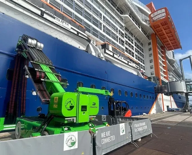 Seitenansicht eines Kreuzfahrtschiffes am Hafen, das an ein iMSPO-Ladesystem angeschlossen ist