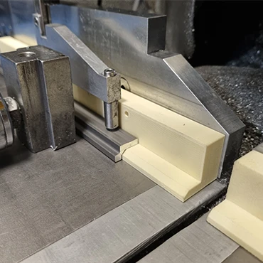 A device manufactured from iglidur I190 in 3D printing so that the rails rest at right angles on the profile saw's working surface.