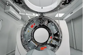 CT-Gerät mit leichter radioaktiver Strahlung. Gezeigt wird ein Gerät mit geöffneter Klappe, sodass das Innenleben mit den zugehörigen Leitungen zu sehen ist.