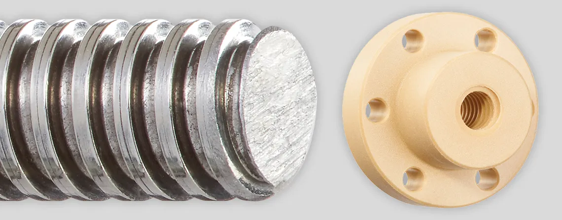 Three ACME lead screw nuts lined up left to right, the first one a white cylinder with a hole with grooves that run counterclockwise in a spiraling rotation to the back of the nut, the middle one a dark maroon red cylinder with a tall rectangle backing that has a rounded top and bottom. There are 3 holes, a small hole at the top of the rectangle and the bottom, and a larger hole with counterclockwise grooves running through it in a spiraling pattern. The nut all the way to the left is light tan/beige, a cylinder with a larger, thinner cylinder backing. The backing has 6 evenly spaced small holes around its face, and the main cylinder has a large hole with counterclockwise grooves spiraling to the back of the nut