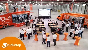Work show in igus hall with people at tables and two roadshow trucks